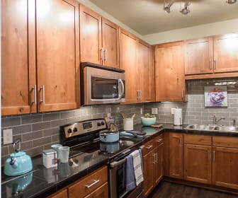 kitchen featuring electric range oven, stainless steel microwave, dark countertops, dark parquet floors, and brown cabinets, Whisper Sky