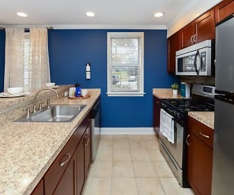 kitchen featuring natural light, gas range oven, stainless steel appliances, light tile floors, light granite-like countertops, and dark brown cabinets, The Villas at Bryn Mawr Apartment Homes