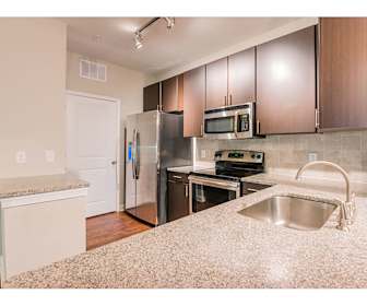 kitchen with stainless steel appliances, electric range oven, light hardwood flooring, light stone countertops, and dark brown cabinetry, Preserve at Belle Hall