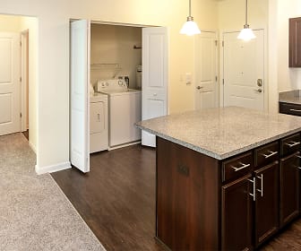 kitchen with carpet, a kitchen island, washer / dryer, electric range oven, microwave, dark brown cabinetry, dark flooring, light granite-like countertops, and pendant lighting, Marquis Place
