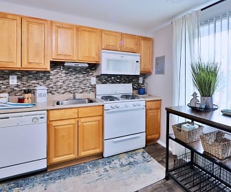 kitchen with a wealth of natural light, range oven, dishwasher, microwave, dark flooring, light countertops, and brown cabinetry, Gwynnbrook Townhomes